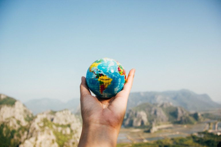 a hand holding a small globe in the air