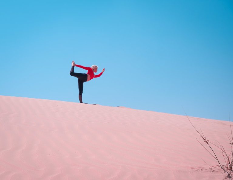 A woman performing yoga atop a desert bank