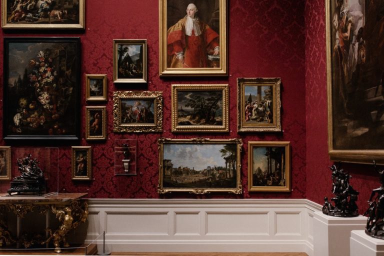 images of paintings on a traditional red wall inside a museum or gallery