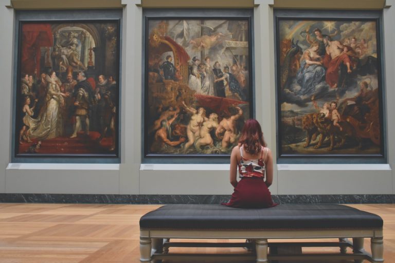A woman sat in a gallery admiring three pieces of art