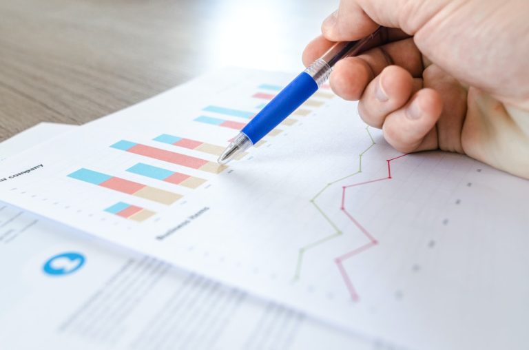 A close up of papers with graphs on, and a pen pointing to it