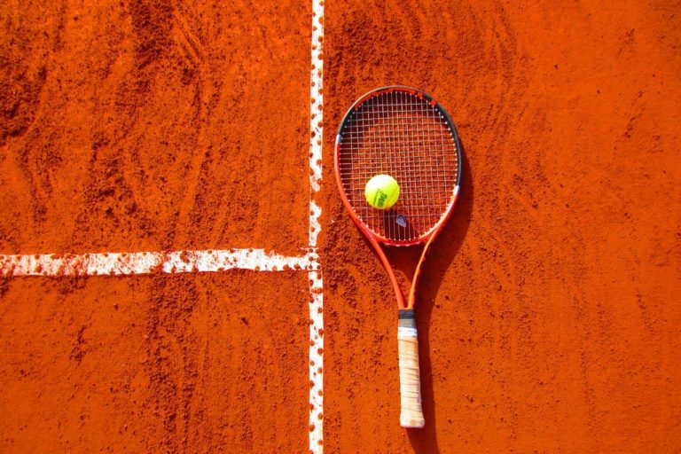 tennis racket and tennis ball on the floor of a tennis court